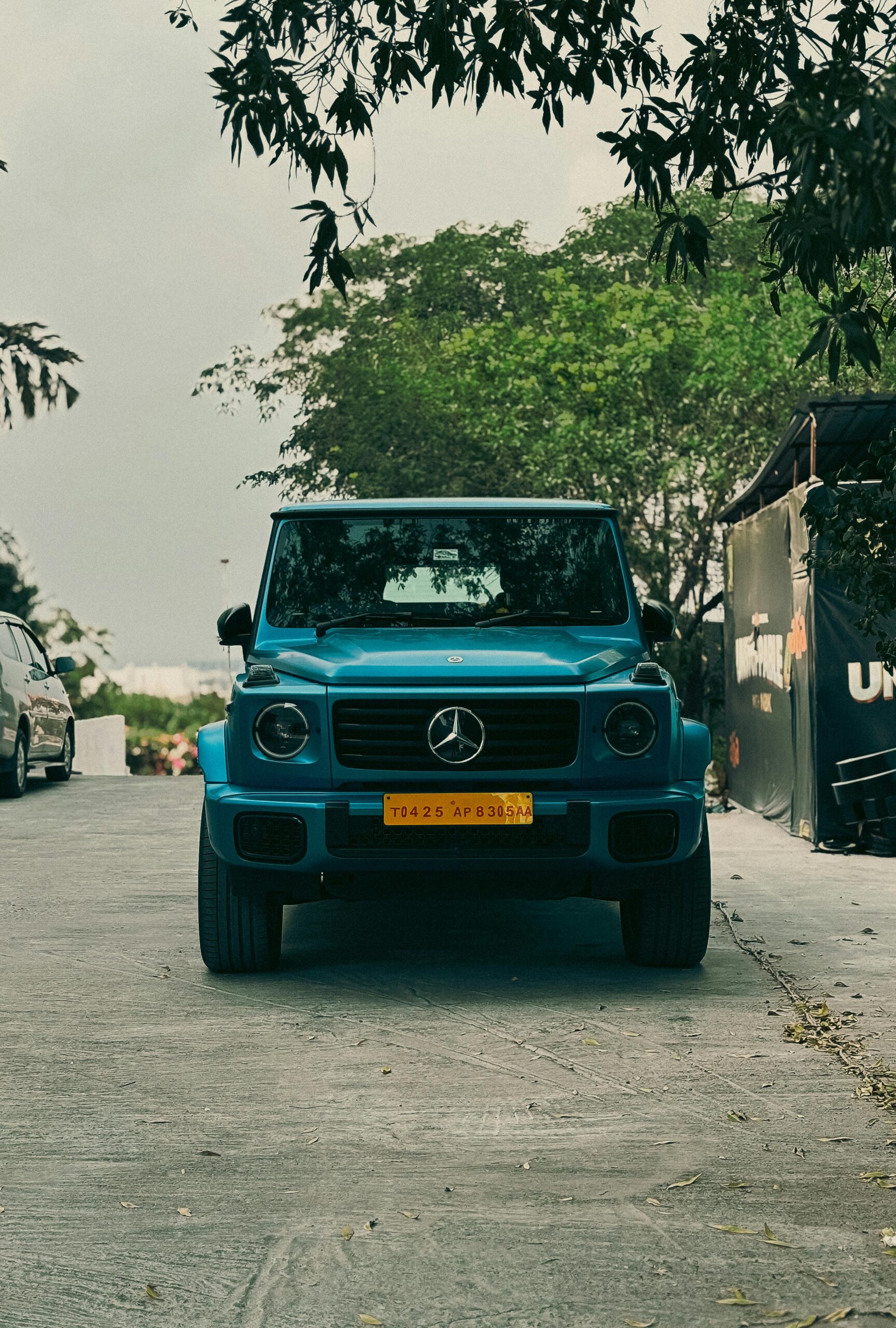 A blue luxury SUV parked on a street in Hyderabad, India, surrounded by greenery.